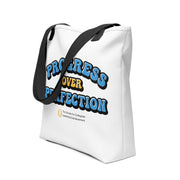 White tote bag with 'Progress Over Perfection' text and black strap on a white background