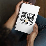 Person holding a notebook with 'Don't Stop Until You're Proud' text