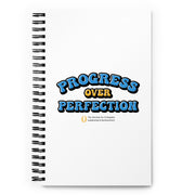 Notebook with 'Progress Over Perfection' text on a white background