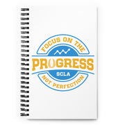 Notebook with 'Focus on the Progress, Not Perfection' design on a white background